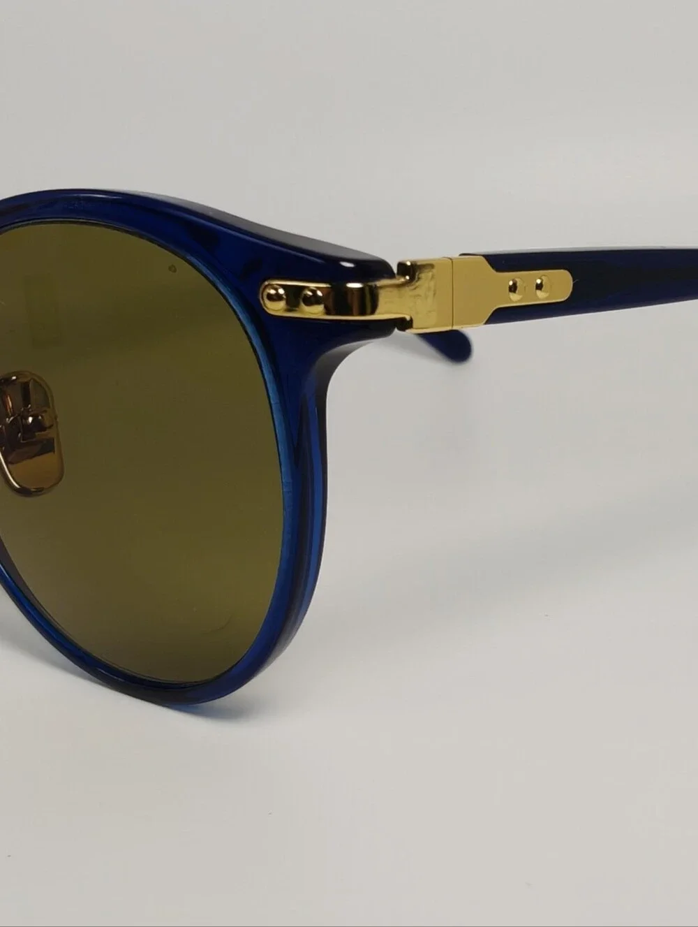 Dotti. Round Navy Translucent frame. Gold Hinge Extends to frame front.